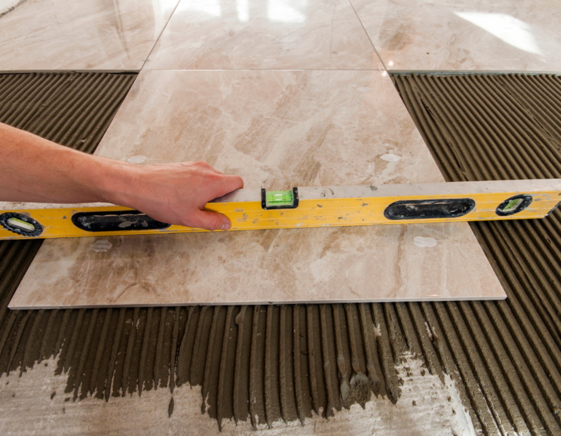 Αλφάδι πάνω σε πλακάκι για να μπουν σωστά τα πλακάκια